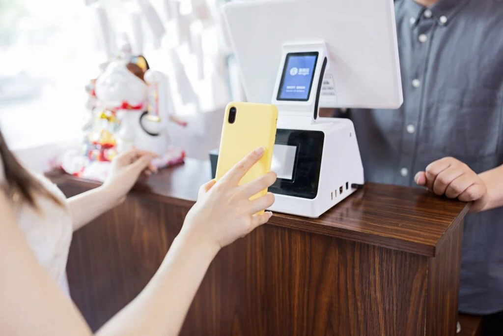 an asian chinese cafe owner businessman receiving payment from customer at counter using QR code
